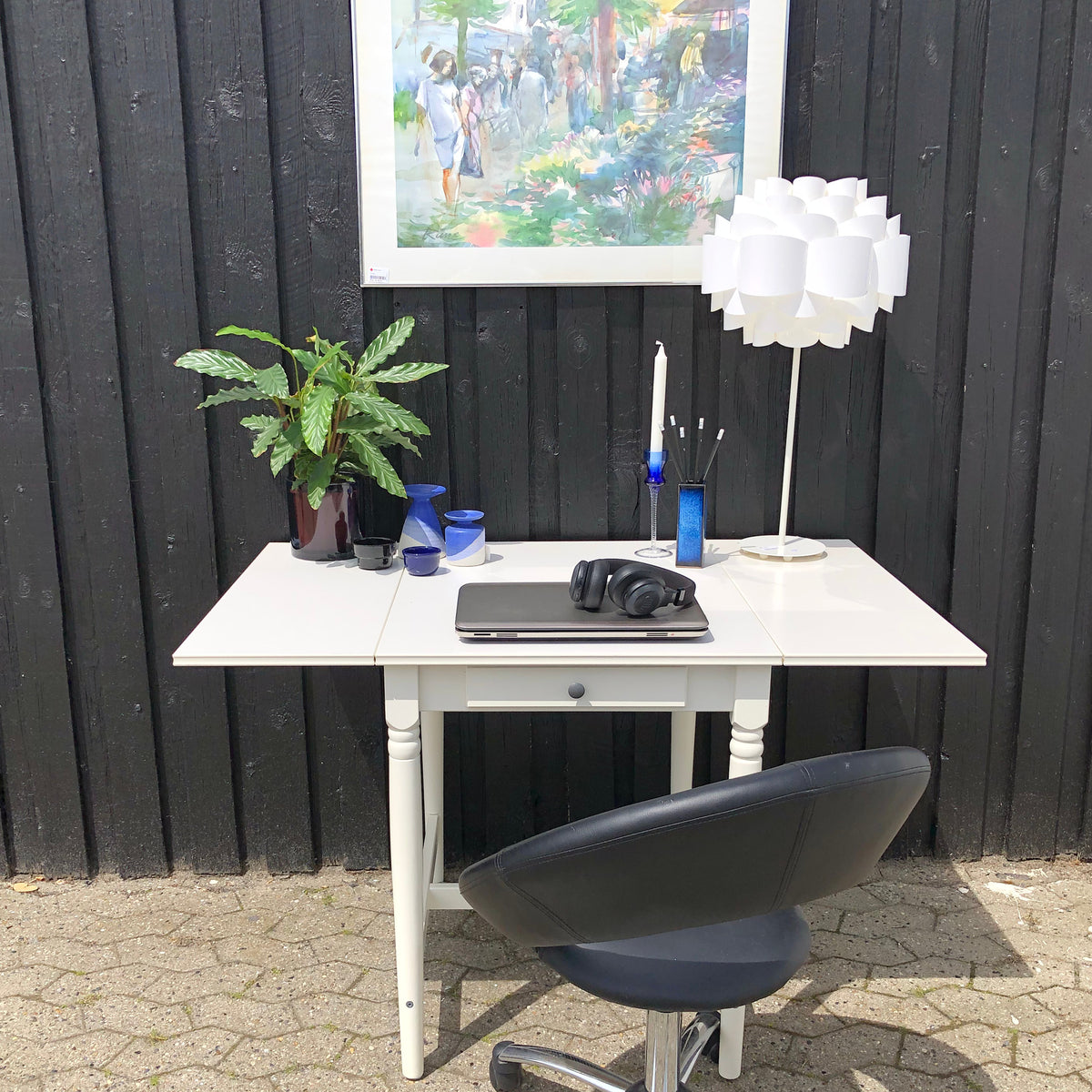 Skrivebord med bordlampe, computer, høretelefoner, plante og glas samt stol fra genbrug